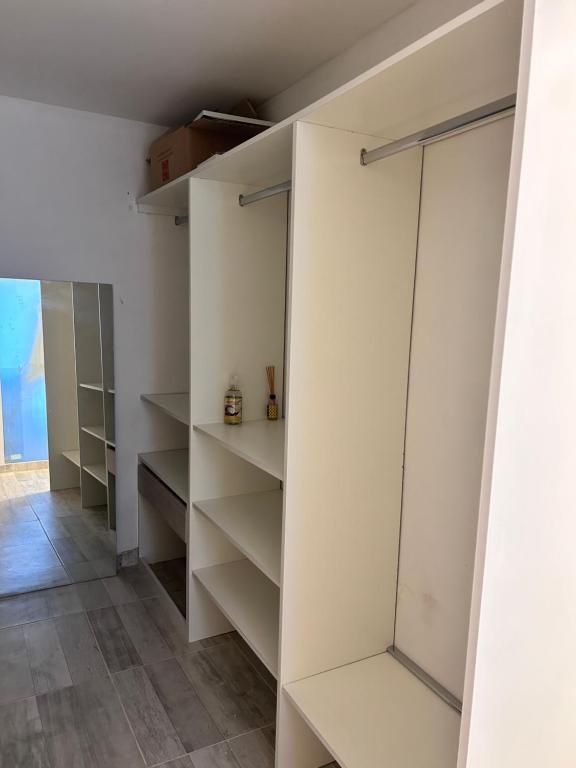 einen begehbaren Kleiderschrank mit weißen Wänden und Regalen in der Unterkunft General Roca hermosa habitacion con baño privado in General Roca