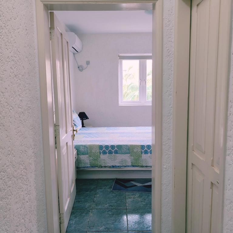 een kleine slaapkamer met een bed en een raam bij White Sand Cabana in Flic-en-Flac