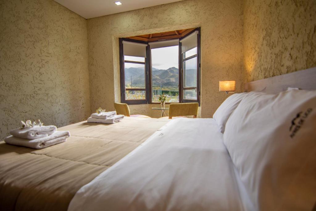 1 dormitorio con 1 cama grande y toallas. en Ayres de Uco Lodge & Wine Lovers en Los Árboles