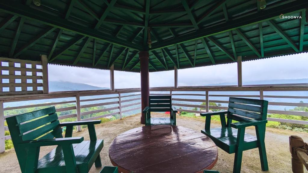 two chairs and a wooden table in a gazebo at Shoonya Mukteshwar in Mukteswar