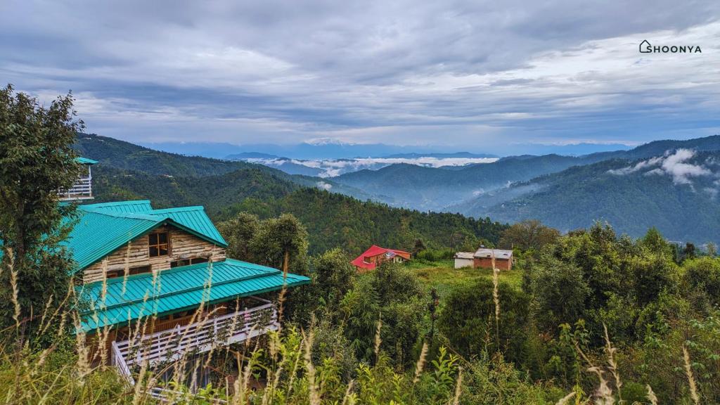 a house with a blue roof on top of a mountain at Shoonya Mukteshwar in Mukteswar