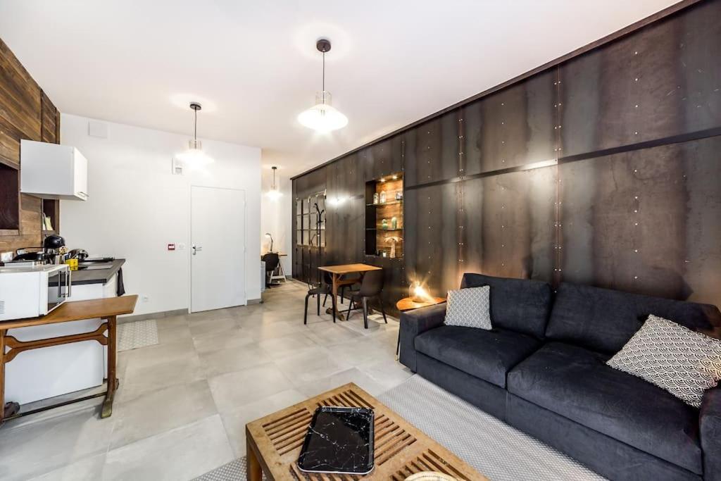 een woonkamer met een bank en een tafel bij Superbe studio style industriel à Charbonnière in Charbonnières-les-Bains