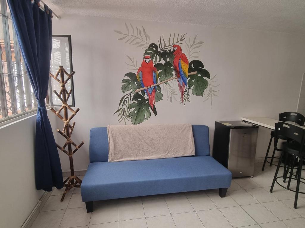 een woonkamer met een blauwe bank en vogels aan de muur bij RoBe Apartmento in Bogota