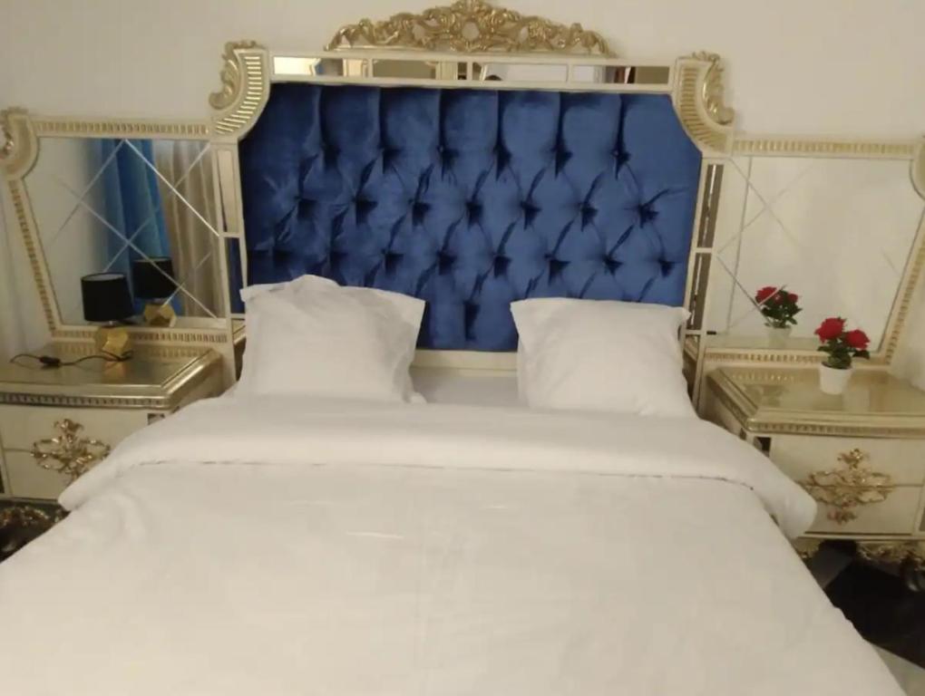 ein großes Bett mit blauem Kopfteil und weißer Bettwäsche in der Unterkunft PARADIS CHAMBRES D'HÔTES PROCHE PARIS - AÉROPORT CHARLES DE GAULLE AIRPORT - PARC DES EXPOSITION VILLEPINTE - DYSNAYLAND PARIS. in Tremblay En France