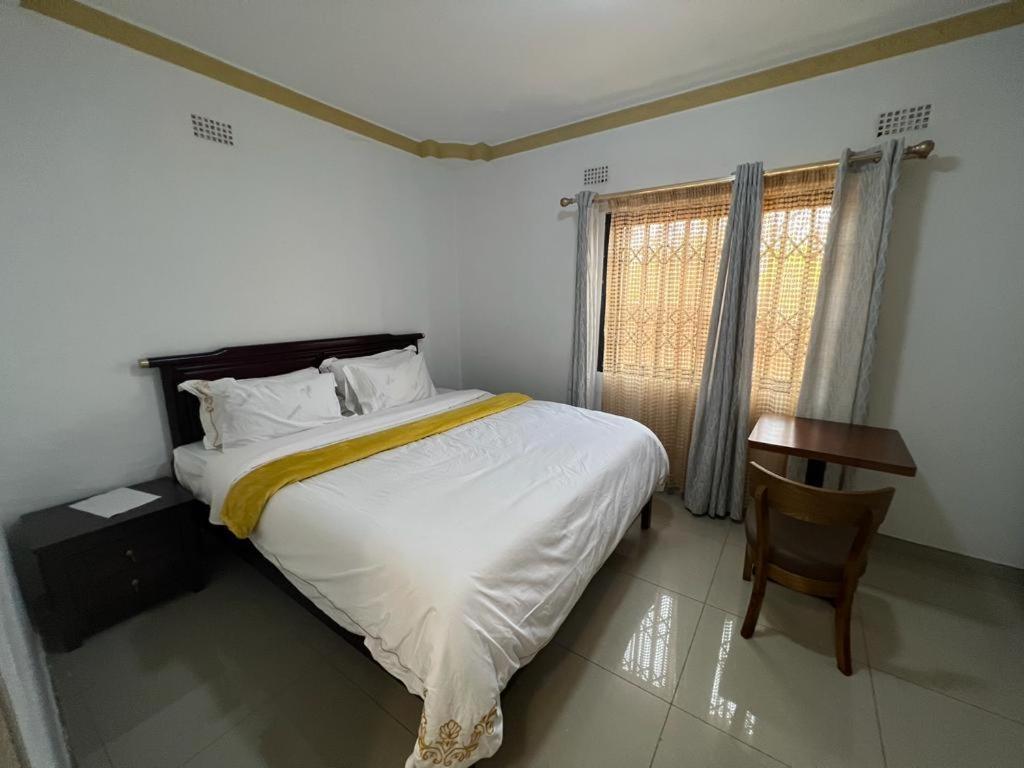 una camera con un letto e una sedia e una finestra di PGD Homes & Lodges a Blantyre