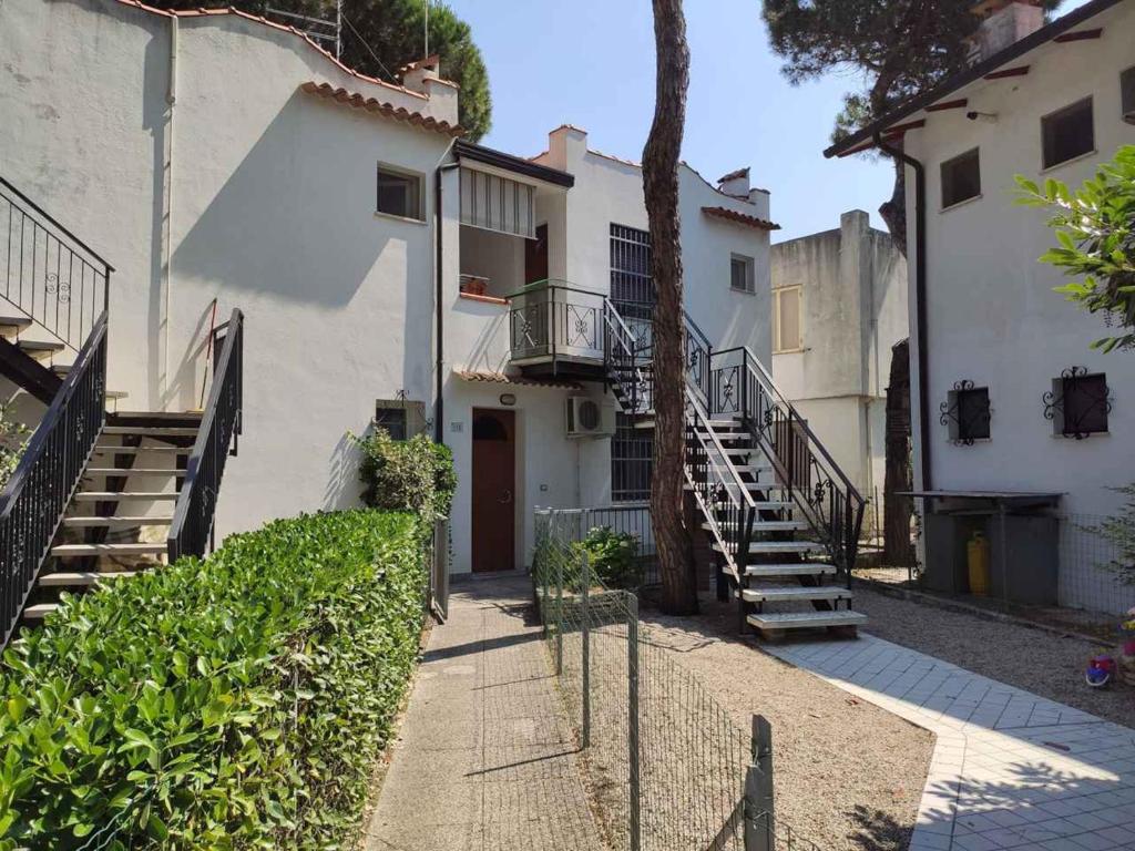 - un bâtiment blanc avec des escaliers menant à une porte dans l'établissement Holiday Homes in Rosolina Mare 48310, à Rosolina Mare