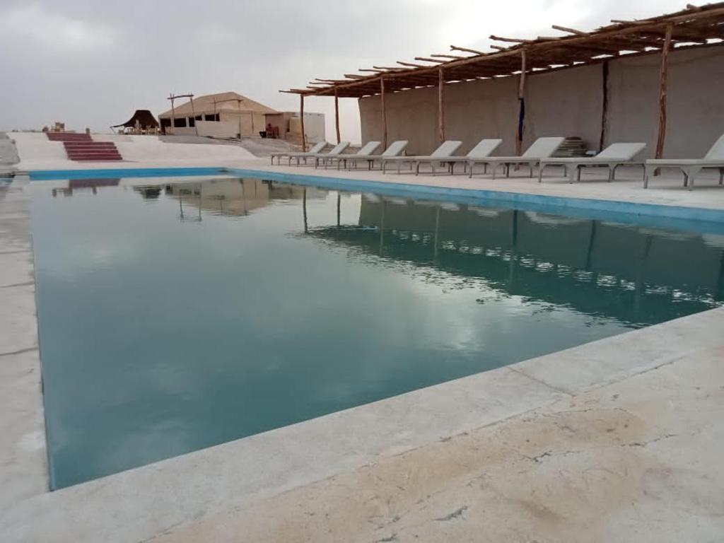 a swimming pool with chairs in the water at Agafay Camp in Marrakech