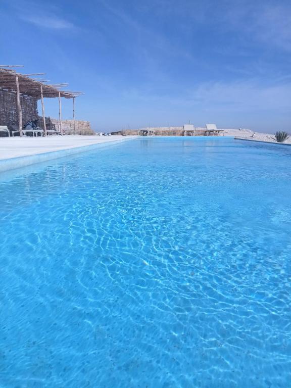 una gran piscina de agua azul junto a una playa en Agafay Camp, en Marrakech