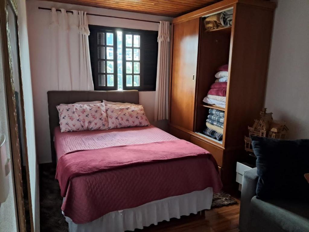 1 dormitorio con cama con sábanas rosas y ventana en Casa de Boneca, en Campos do Jordão