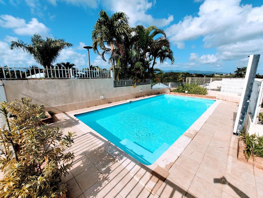 una piscina en un patio trasero con árboles y una valla en Le Nil Appartement Cosy tout confort, en Baie-Mahault