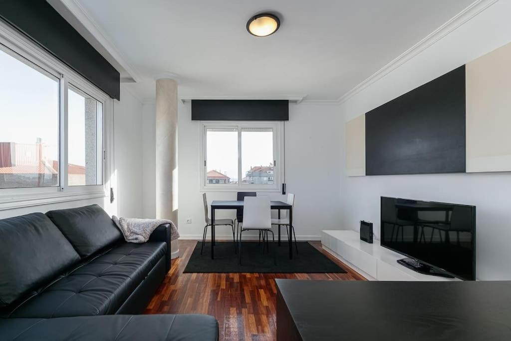 a living room with a black couch and a table at Moderno piso en el corazón de Baiona by CABANA Rentals in Baiona