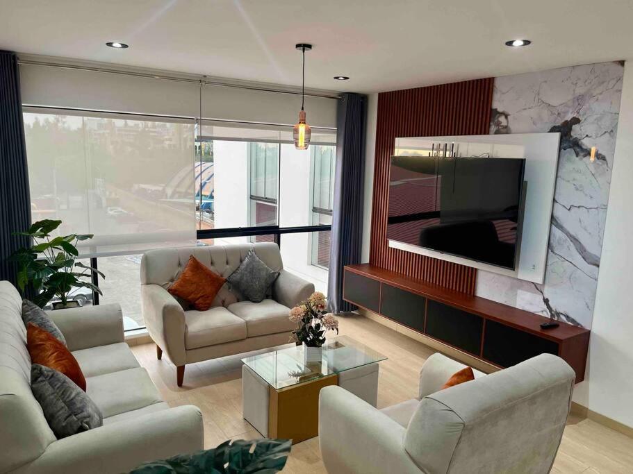 sala de estar con 2 sofás y TV de pantalla plana en Moderno departamento Vallecito, en Arequipa