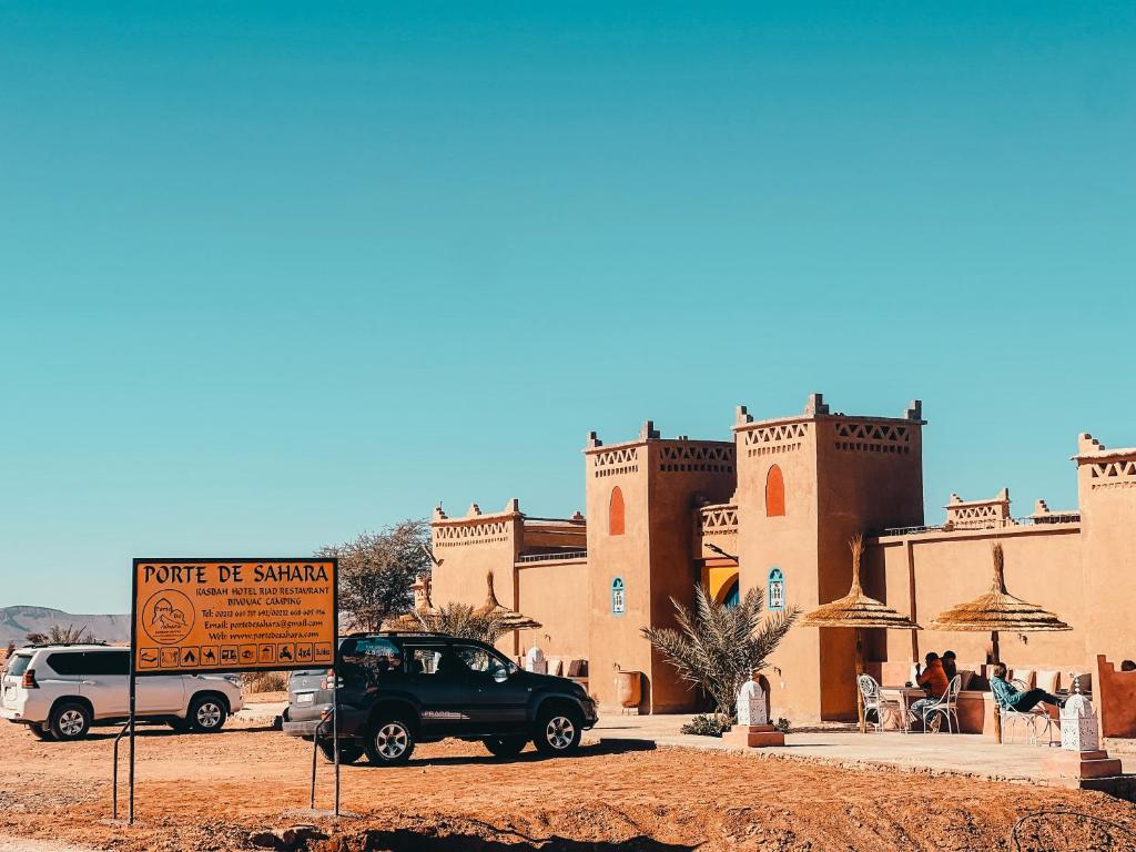 un camión estacionado frente a un edificio en el desierto en Porte De Sahara Ouzina en Ouzina