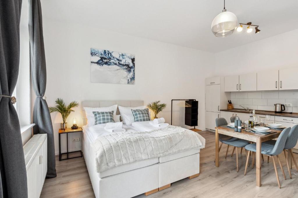 1 dormitorio blanco con 1 cama y cocina en Homespace - Magdeburg - Gemütliches Apartment mit Balkon en Magdeburgo