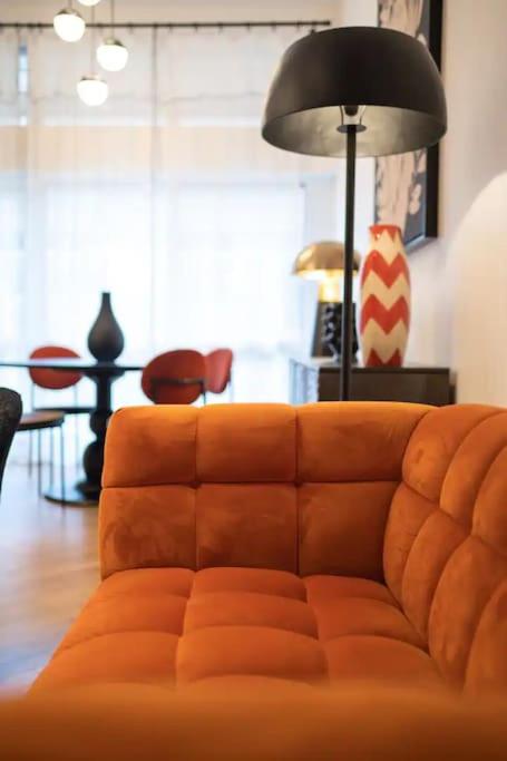 an orange couch in a living room with a lamp at E Fauvette appartement de standing avec terrasse in Épernay