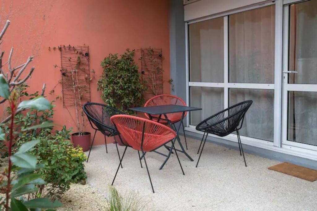 three chairs and a table in front of a building at E Fauvette appartement de standing avec terrasse in Épernay