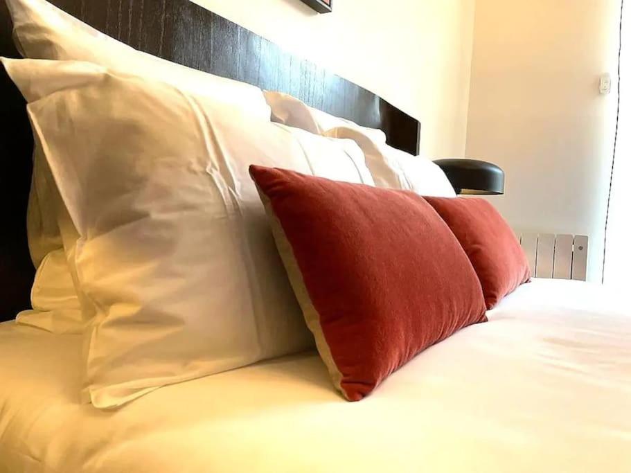 a bed with red and white pillows on it at E Fauvette appartement de standing avec terrasse in Épernay