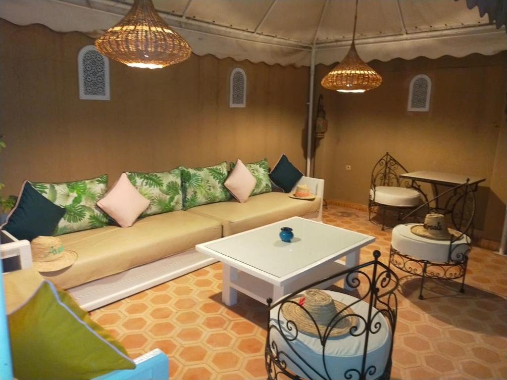 a living room with a couch and a table at RIAD AWINATI Location Privatisée ,piscine chauffée in Marrakesh