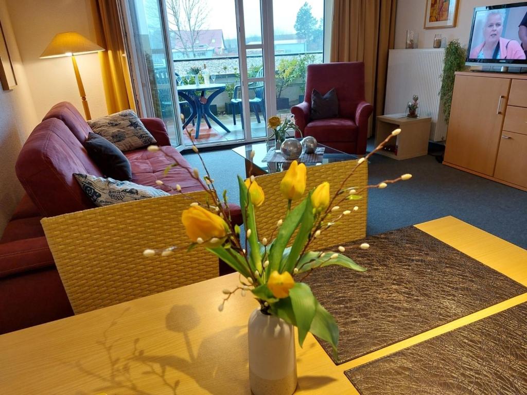 ein Wohnzimmer mit einer Blumenvase auf dem Tisch in der Unterkunft de Leuchtviol in Dorum Neufeld