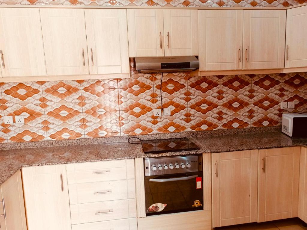 a kitchen with white cabinets and a stove top oven at Kigali Peace vill in Kigali