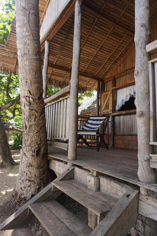 a porch of a wooden cabin with a tree at Chez Antonio in Ampasimena