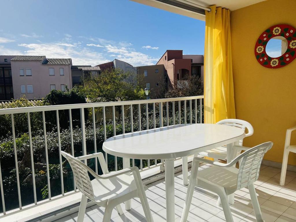une table blanche et des chaises sur un balcon avec vue dans l'établissement ARCHIPEL III Joli 2 Pièces avec clim réversible proche plage Richelieu Piscine Cap d'Agde, au Cap d'Agde