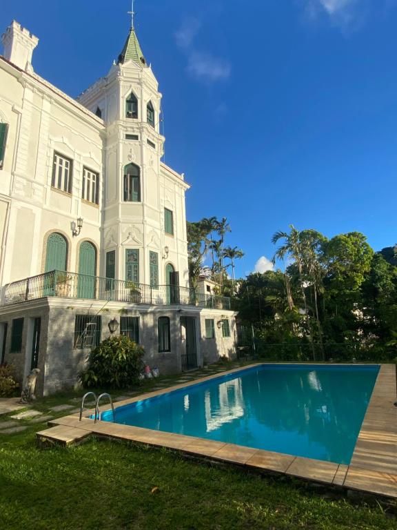 a large white building with a swimming pool in front of it at Castelo dos Tucanos Hostel in Rio de Janeiro