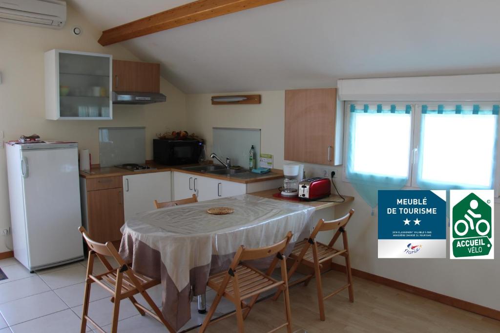 une cuisine avec une table avec des chaises et un réfrigérateur dans l'établissement Meublé 2* climatisé dans un quartier calme, à Dijon