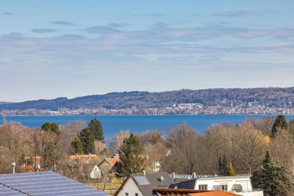 a view of a lake and a town with a solar array at Gemütliches Wohlfühl-Appartment - Kamin - perfekter Seeblick in Dießen am Ammersee