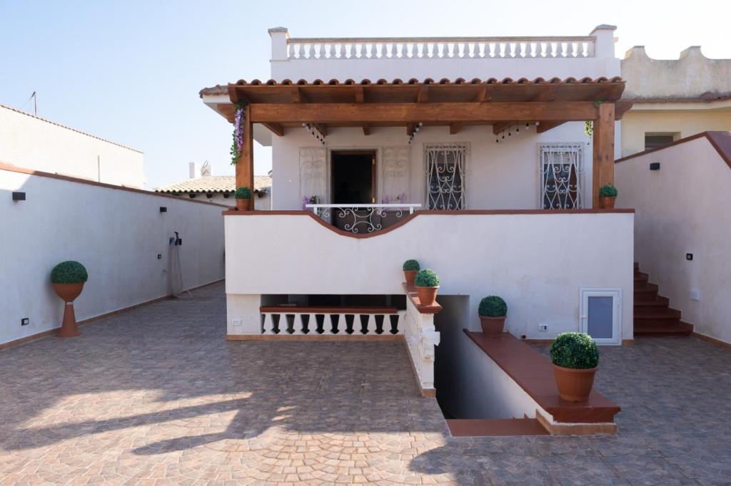 une maison blanche avec des plantes en pot dans la cour dans l'établissement Villa Zaccaria - villetta indipendente, à Mazara del Vallo