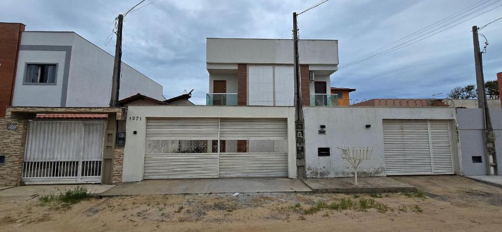 een wit huis met twee garagedeuren en een basketbalring bij Casa Temporada Barra-Mar in Guriri
