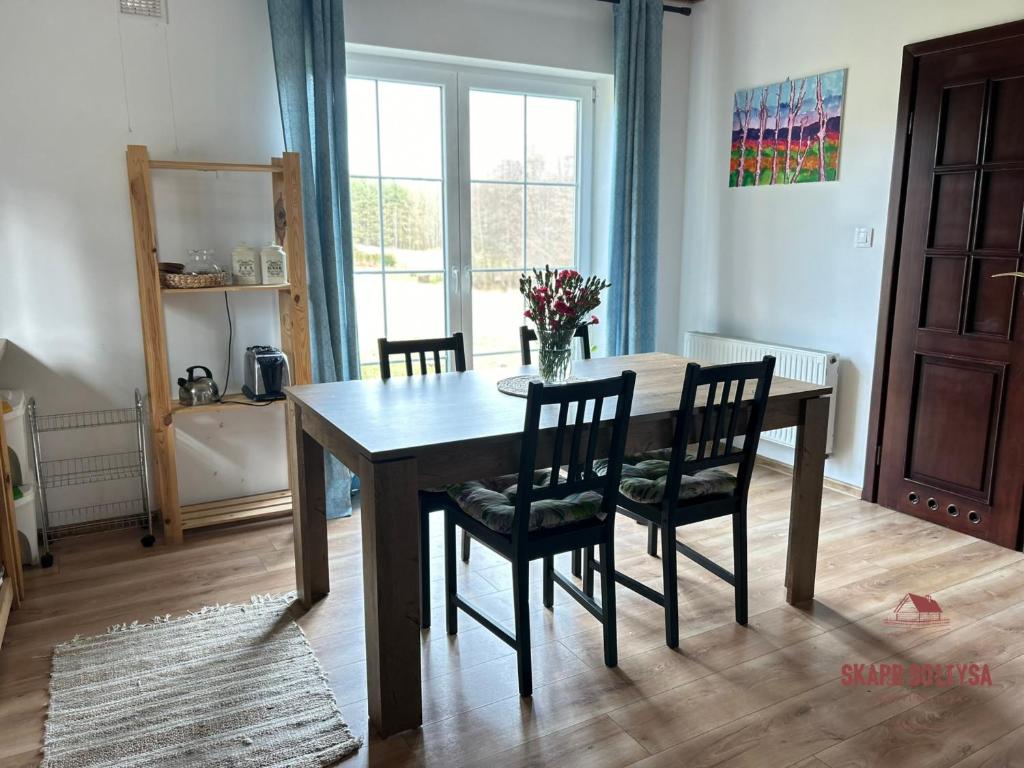 a dining room table with chairs and a vase of flowers at Skarb Sołtysa - apartament z widokiem in Jedwabno
