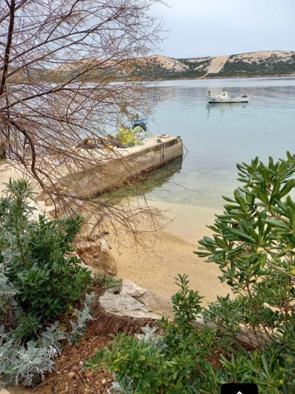a boat in the water next to a beach at APARTMANI KATJA in Stara Novalja