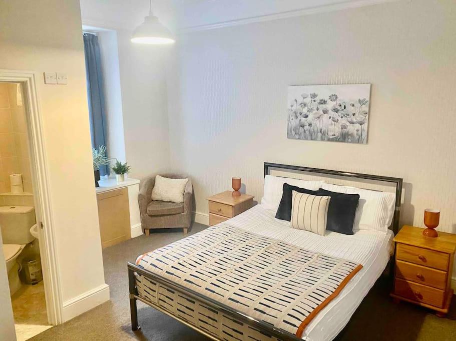 a bedroom with a large bed and a chair at Bright 2 Bedroom Apartment near Seafront Central Penzance in Penzance