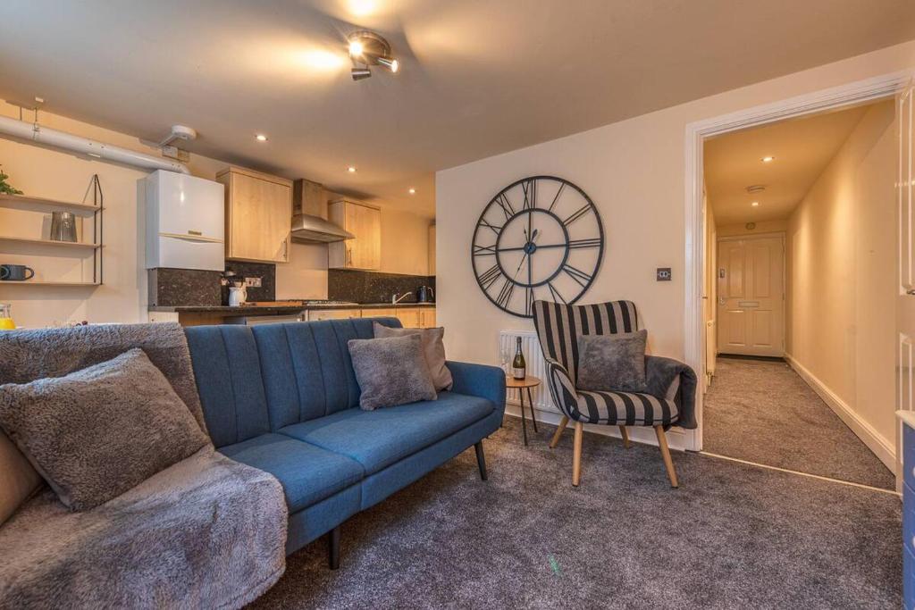 a living room with a blue couch and a clock on the wall at Pass the Keys Modern Ground Floor Apartment in Shifnal