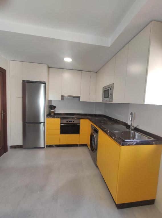 a kitchen with yellow cabinets and a stainless steel refrigerator at Granada Home Center in Granada