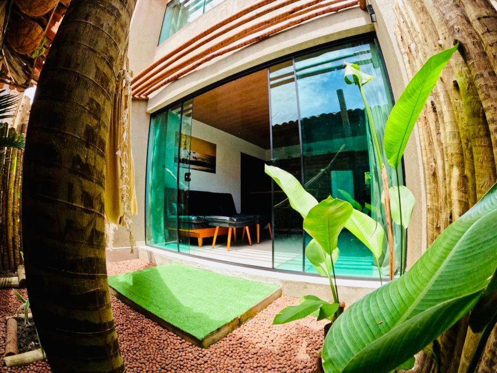 a house with a large window and a palm tree at Ubud Apartments Praia do Frances in Praia do Frances