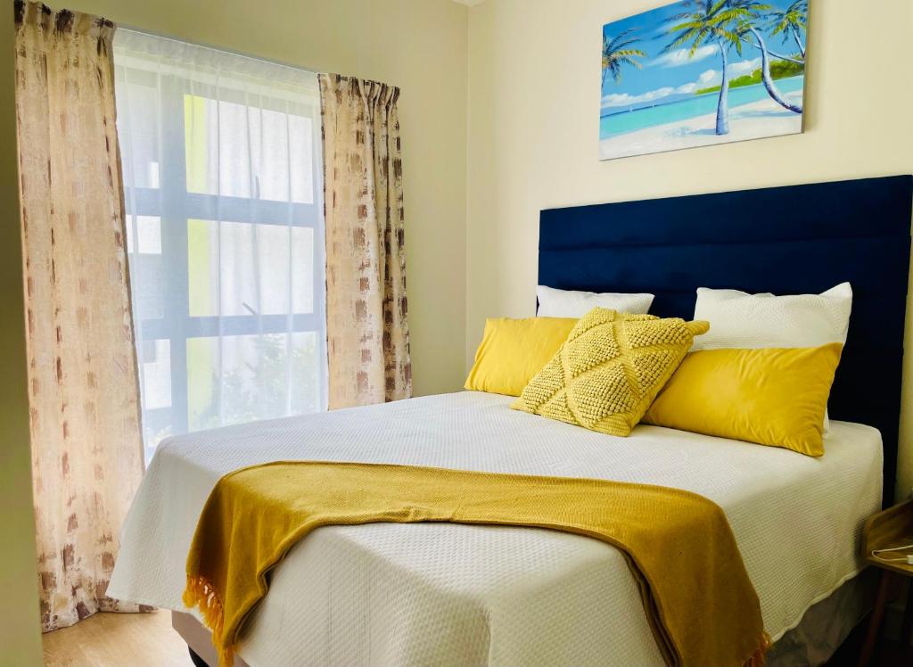 a bedroom with a bed with yellow pillows and a window at 2 Bedroom 2 Bathroom Apartment in Sandton in Johannesburg