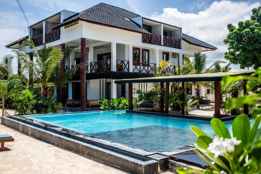 a villa with a swimming pool in front of a house at Baobab Bungalows in Jambiani