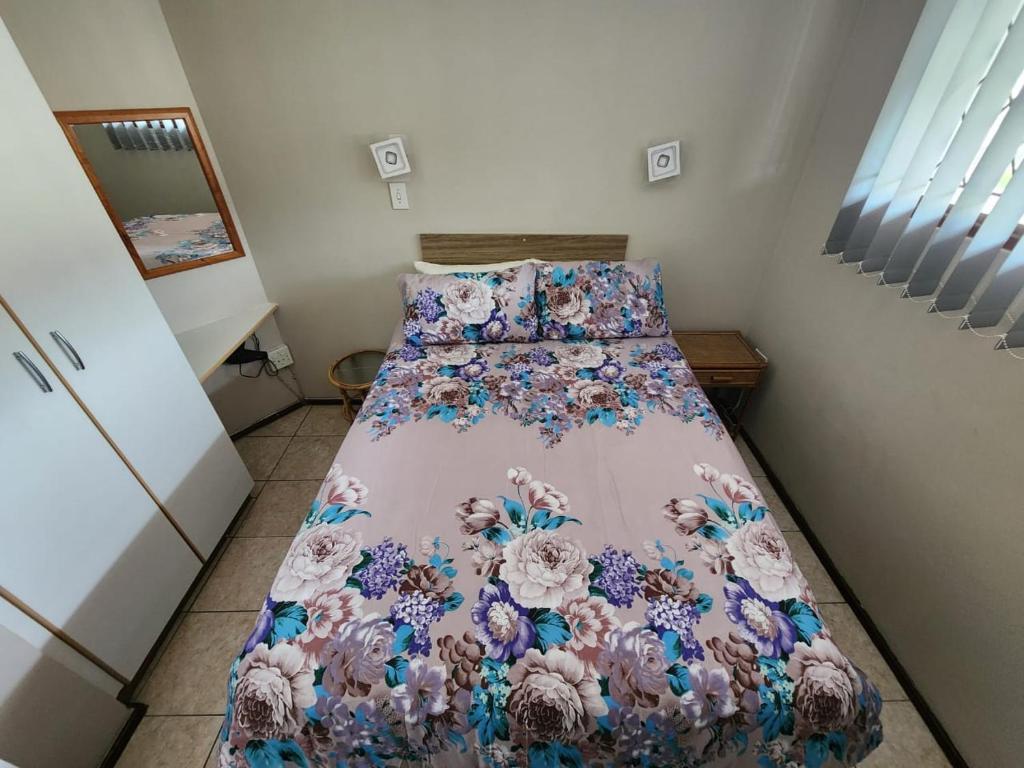 a bedroom with a bed with a floral bedspread at SurfBay Sands 65 in Shelly Beach