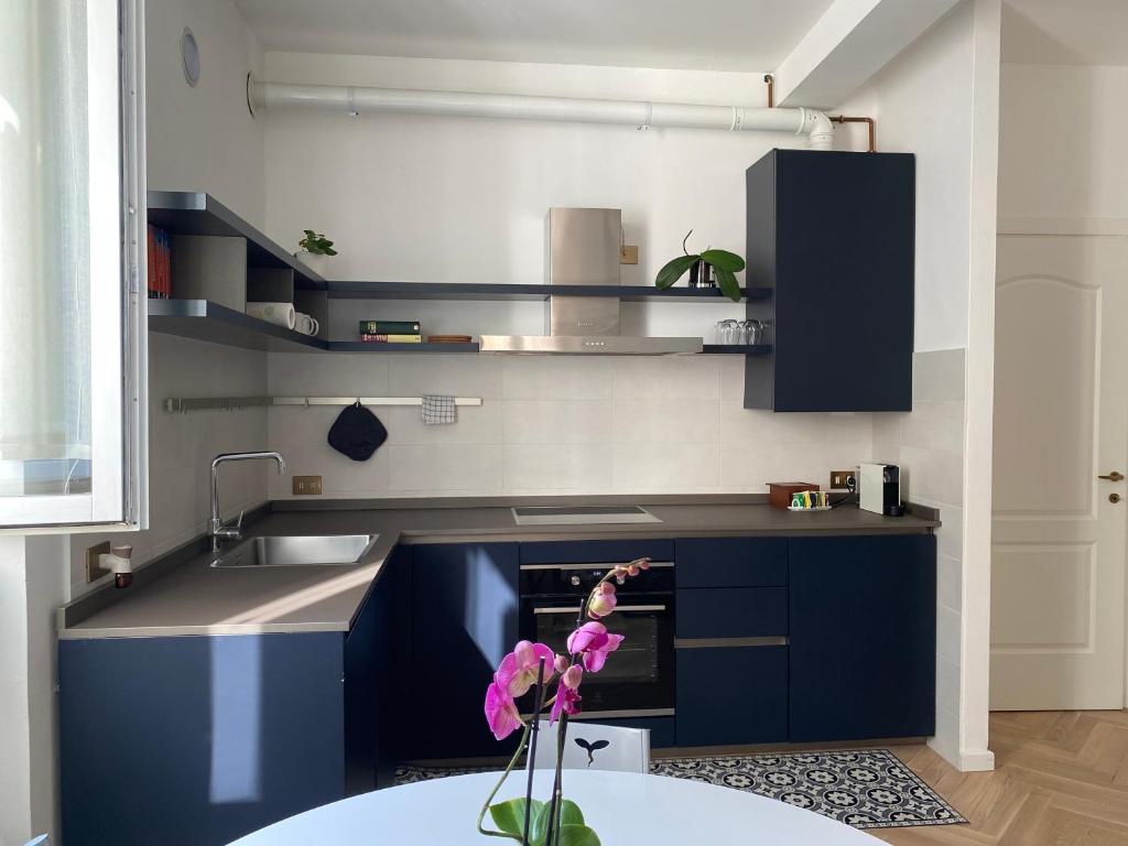 una cucina con armadi blu e un fiore in un vaso di WANDERLUST Splendido appartamento in centro a Pavia