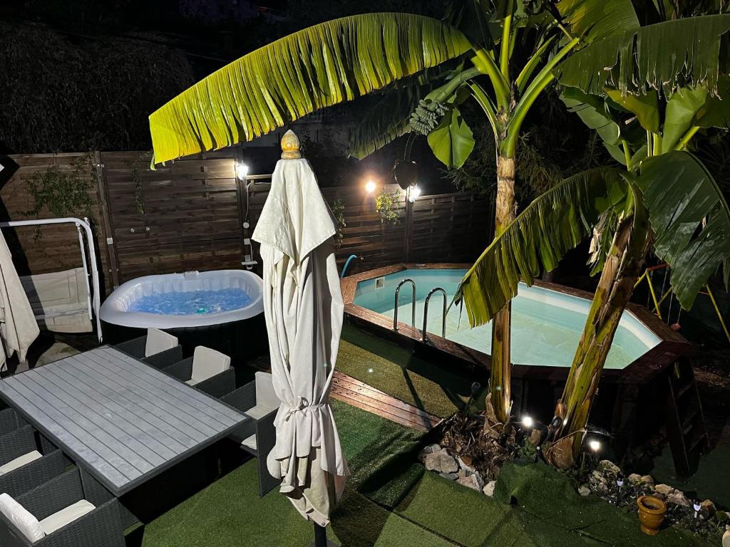 a swimming pool with a umbrella next to a tub at Petit coin de paradis in Menton