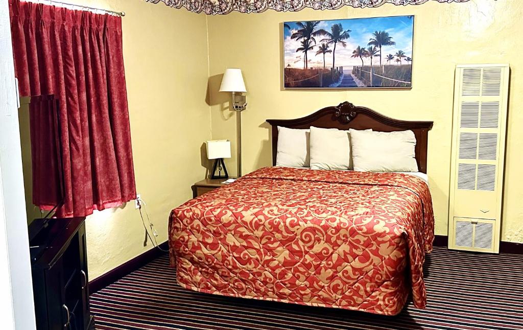 a hotel room with a bed with a red bedspread at Relax Inn Vinita in Vinita