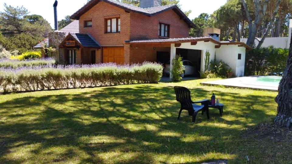 un banco sentado en el césped frente a una casa en Chalet con Piscina exclusiva en el centro de Mar de las Pampas en Mar de las Pampas