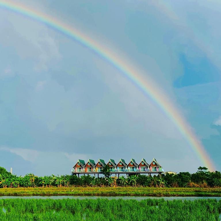 a rainbow over a row of houses and a field at Kitefarm in Dongshan