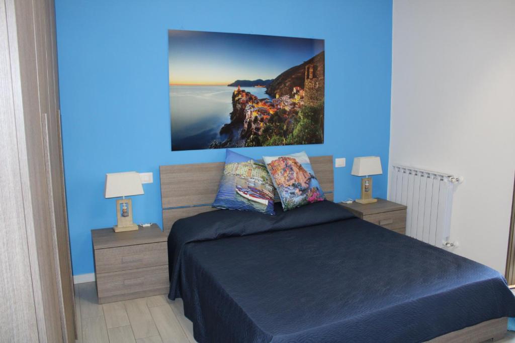 una camera da letto con una parete blu, un letto e 2 lampade di Speziamare a La Spezia