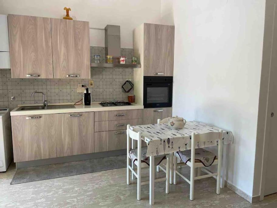 een keuken met houten kasten en een tafel met stoelen bij Trilocale con incantevole giardino in Pietra Ligure