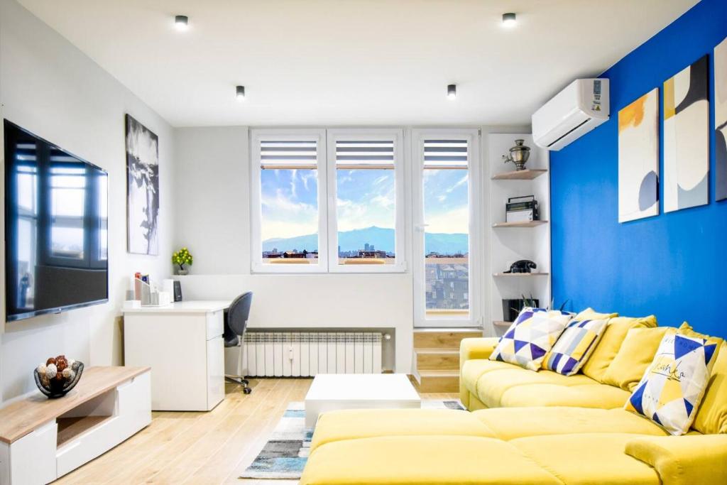 a living room with a yellow couch and a blue accent wall at 180 Panoramic Views Fully Equipped For 6 Acs in Sofia