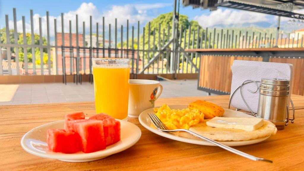 a table with a plate of fruit and a glass of orange juice at Seven hotel in Santa Fe de Antioquia