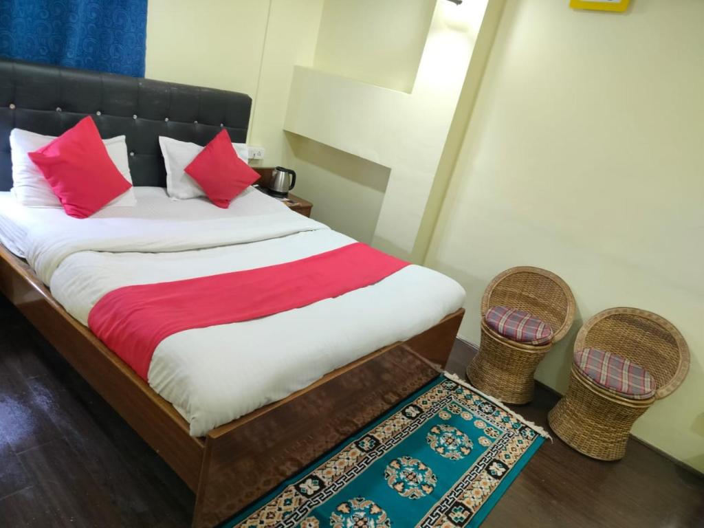 a bedroom with a bed with red pillows and a rug at HOTEL TASHI NORLING Near Mall Road in Gangtok